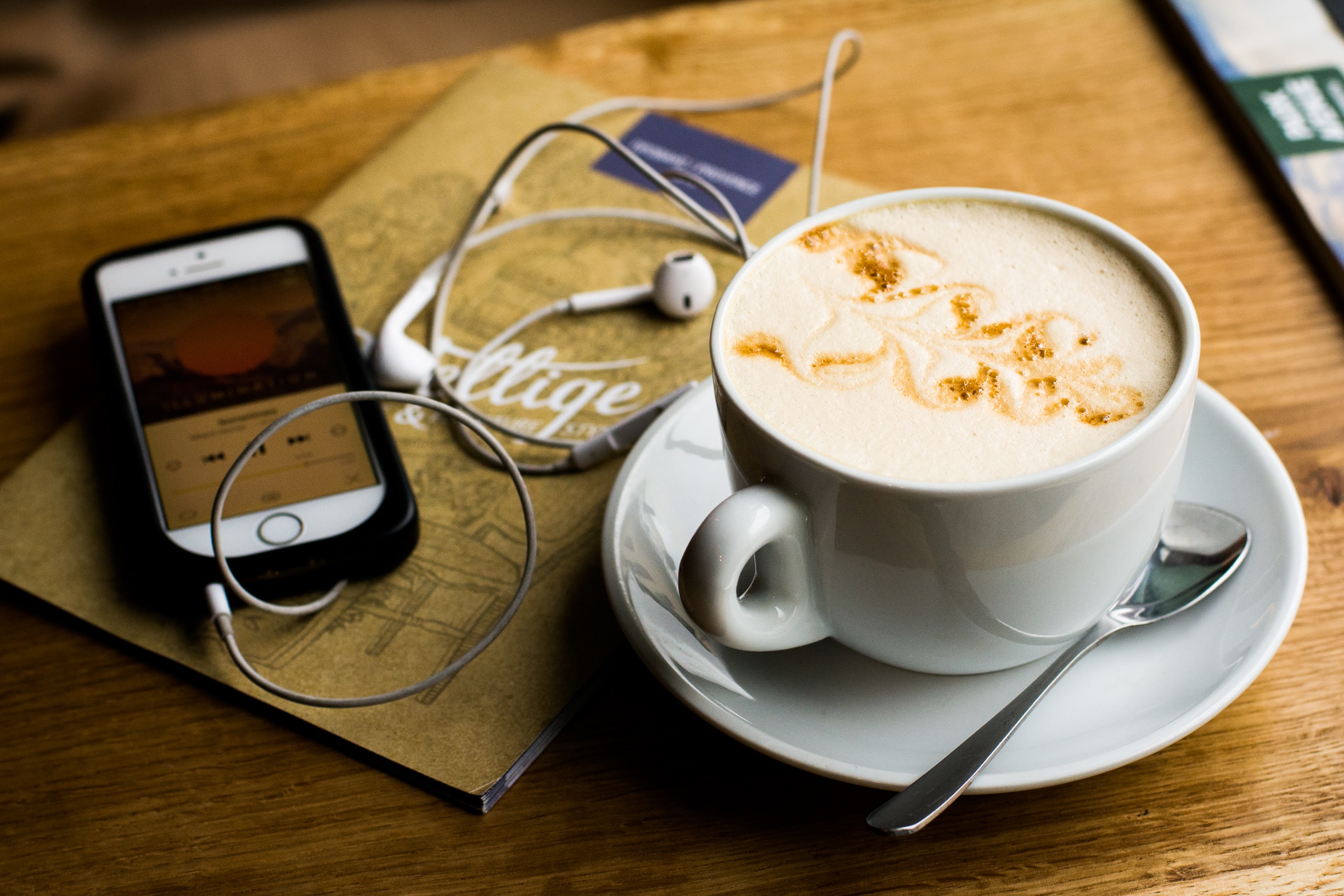 Uno smartphone su cui è in ascolto un podcast, accanto a un cappuccino